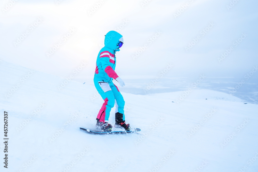 woman snowboarder is snowboarding from the slope woman snowboarder is snowboarding from the slope