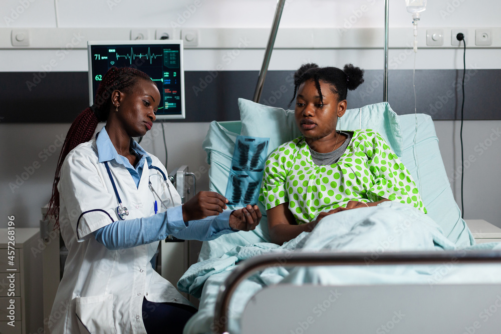 Woman with doctor occupation holding x ray results with patient in ...