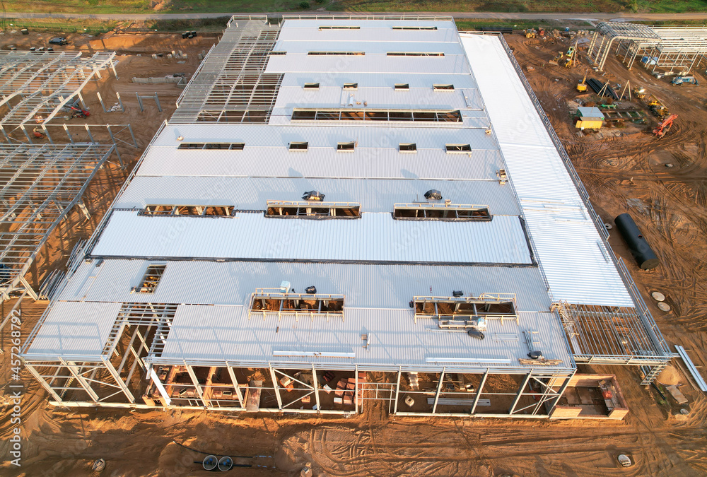 Warehouse Construction from metal structure. Industrial building on light gauge steel framing. Frame of modern hangar or factory. Construction site with steel structure warehouse. Top view on a roof.