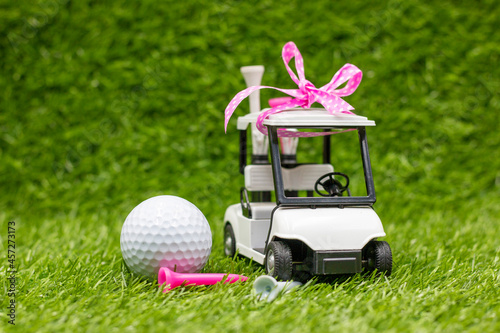 Golf cart is on green grass with pink ribbon for golf women tournament 