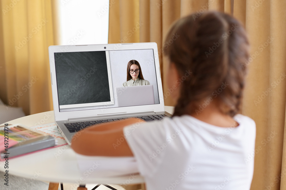 Back view of dark haired girl with pi tails sitting at desk at home on quarantine talk on video call with teacher, schoolgirl have online webcam conversation, engaged in web lesson.