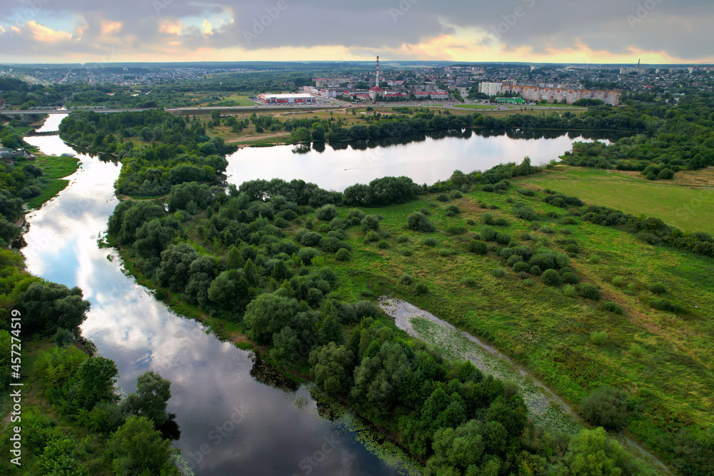 Aerial view of the river against the background of cloudy clouds in rainy weather. Wetlands near the countryside. Soft focus.