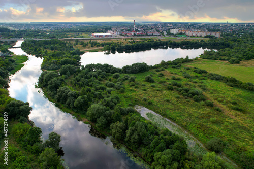 Aerial view of the river against the background of cloudy clouds in rainy weather. Wetlands near the countryside. Soft focus. © MaxSafaniuk