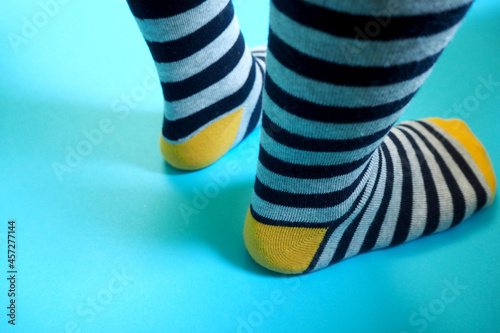 the child's legs on a blue background in striped gray-yellow socks. rear view