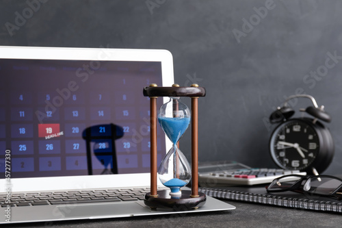 Hourglass and laptop on dar...