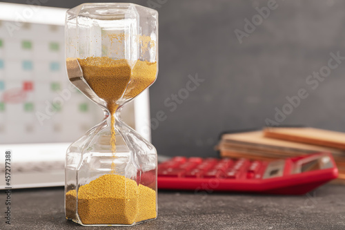 Hourglass and laptop on dar...