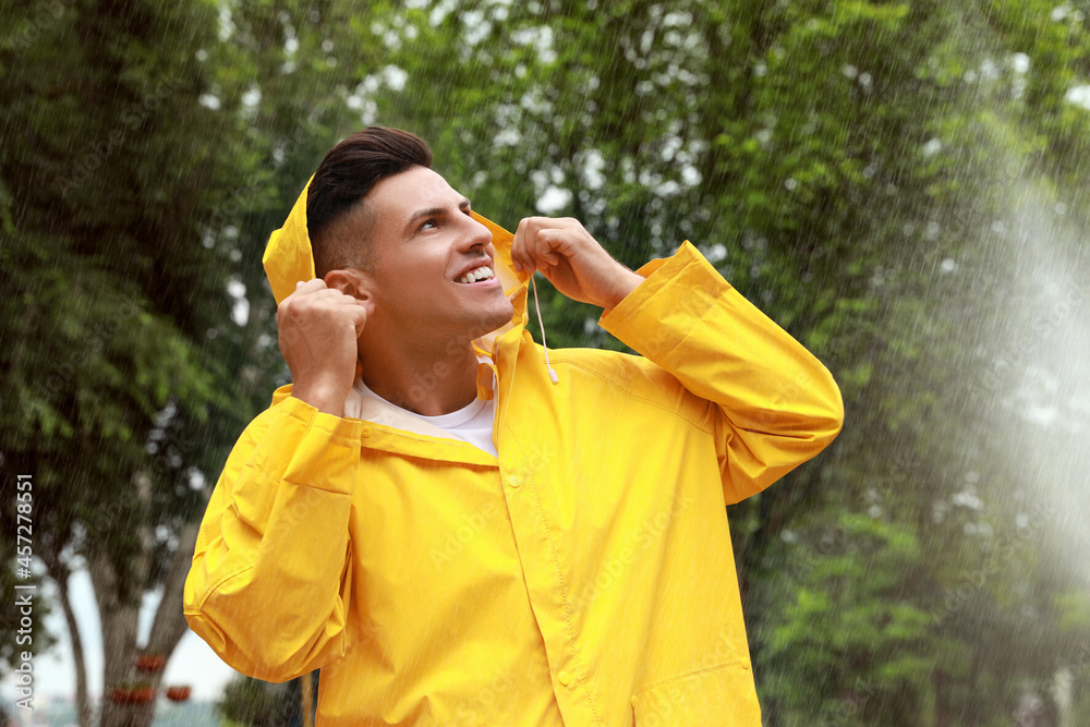 Man with raincoat walking under rain in park Man with raincoat walking under rain in park