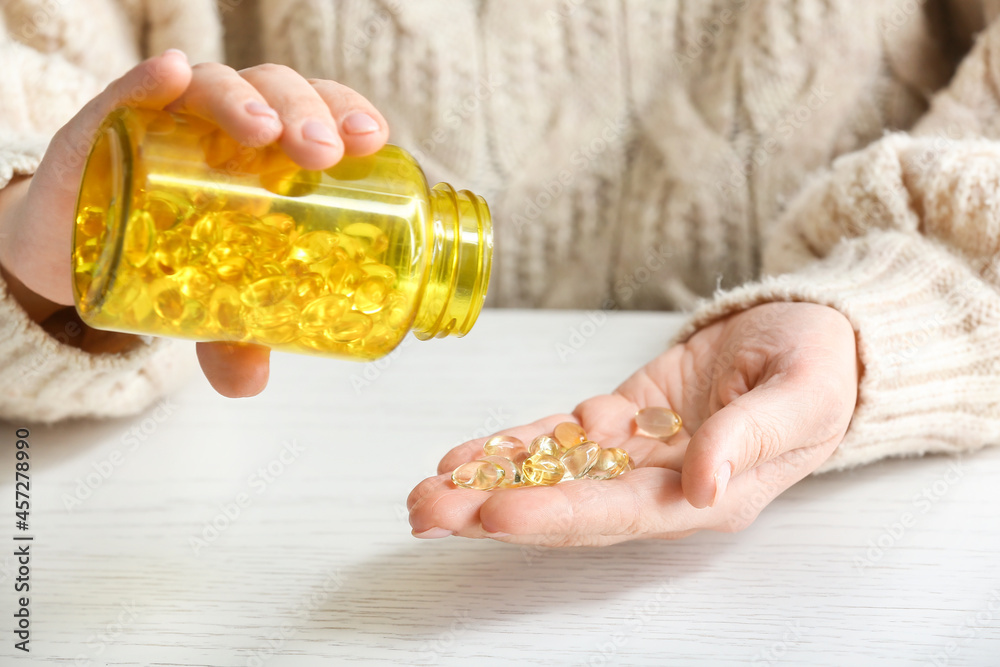 Woman taking fish oil pills at table, closeup Stock Photo Adobe Stock