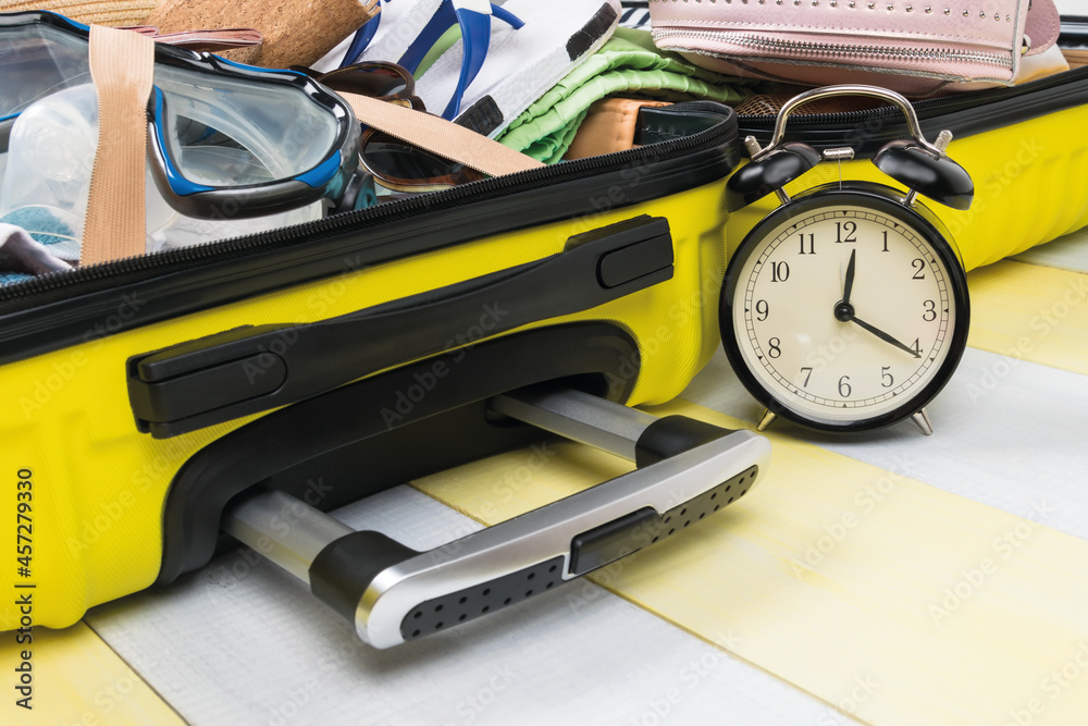 open suitcase on a gray-yellow background with things for rest side view, close-up: time to prepare for vacation