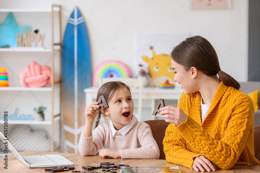 Speech therapist working with cute girl in clinic - obrazy, fototapety, plakaty 