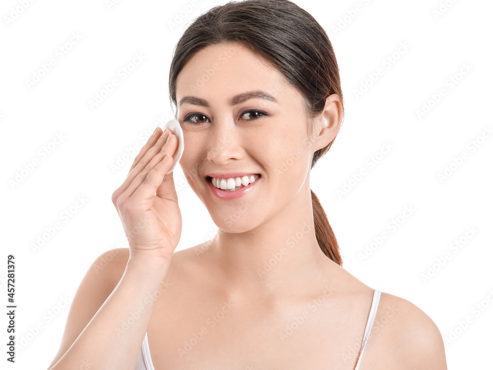 Beautiful young Asian woman with cotton pad on white background