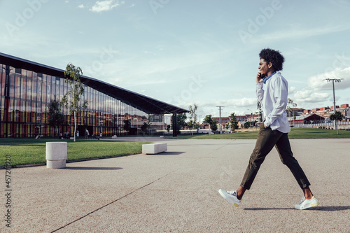 Side portrait of a young african american man walking and talking on cell phone