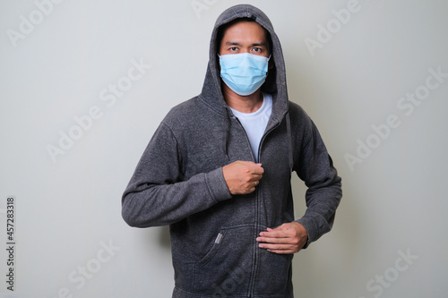 A man zip his hoodie and wearing protective medical mask photo