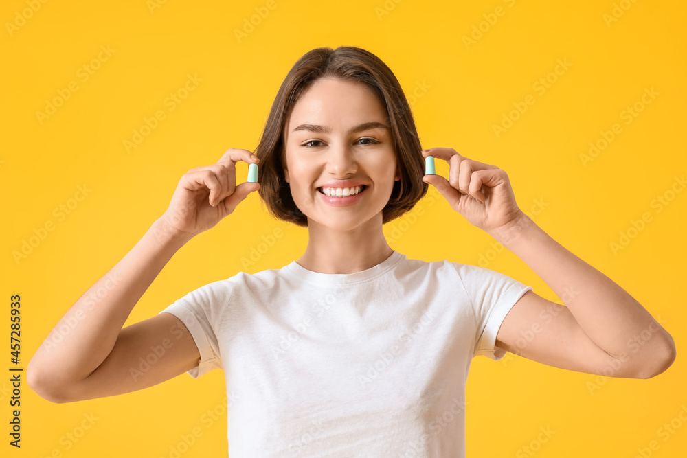 Young woman with ear plugs on yellow background Young woman with ear plugs on yellow background