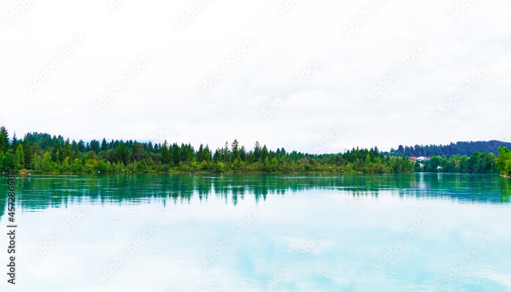 Lech reservoir in Lechbruck am See. View of the lake with the surrounding nature. Reflection in the water. Lech reservoir in Lechbruck am See. View of the lake with the surrounding nature. Reflection in the water.