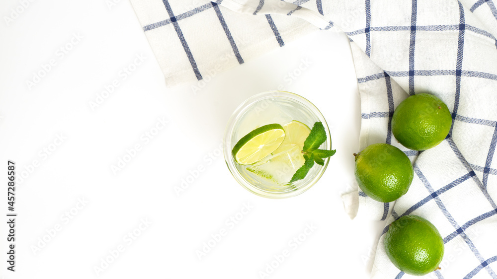 Cut lime and lime water into baking soda in a glass with a straw. Refreshing shot on a white background of a summer party.