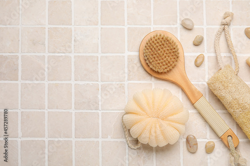 Composition with body brush and bath supplies on light tile background
