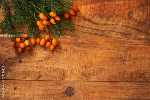 Winter, warm atmosphere. Frame rose berries and spruce on wooden background