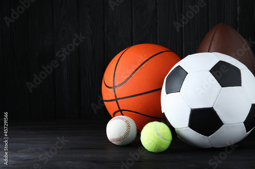 Set of different sport balls on black wooden table. Space for text