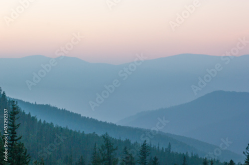 Blurred background smoky mountain landscape with mountain silhouette at sunset. © Vladislav Fokin