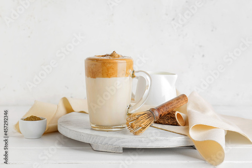 Glass cup of tasty dalgona hojicha latte and chasen on light background photo