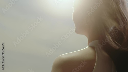 close-up rear view of Asian beauty standing and facing the sun with long hair flying in wind