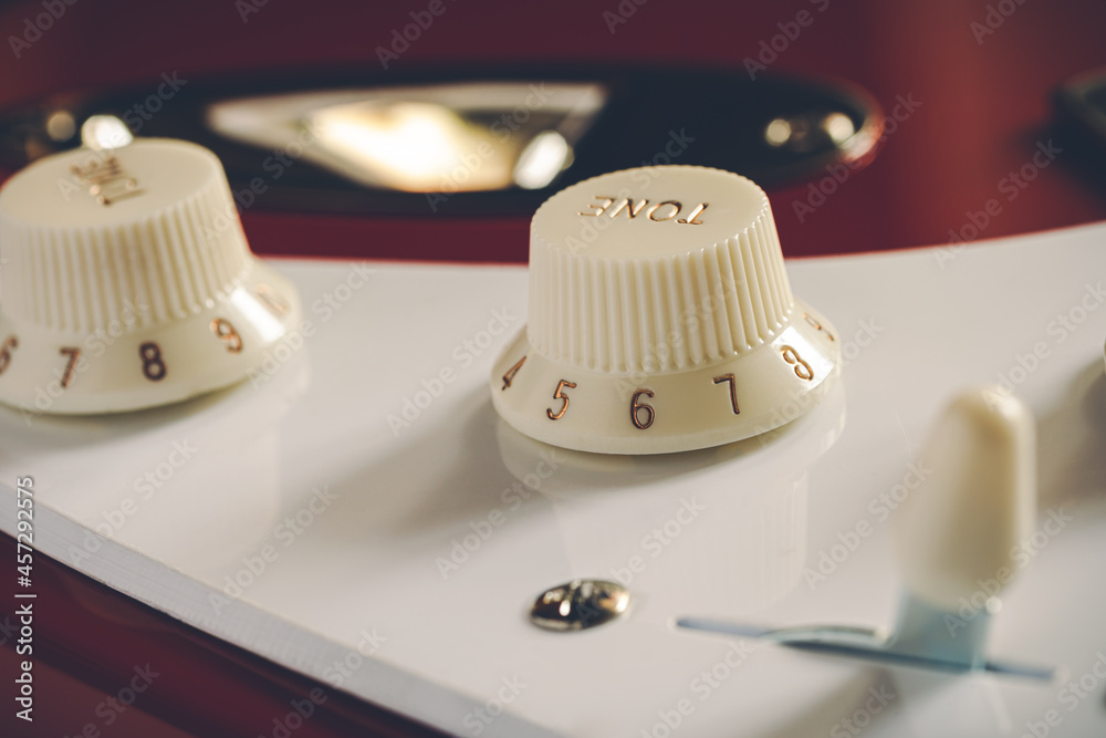 Detail of the volume and tone knobs of a red electric guitar Detail of the volume and tone knobs of a red electric guitar