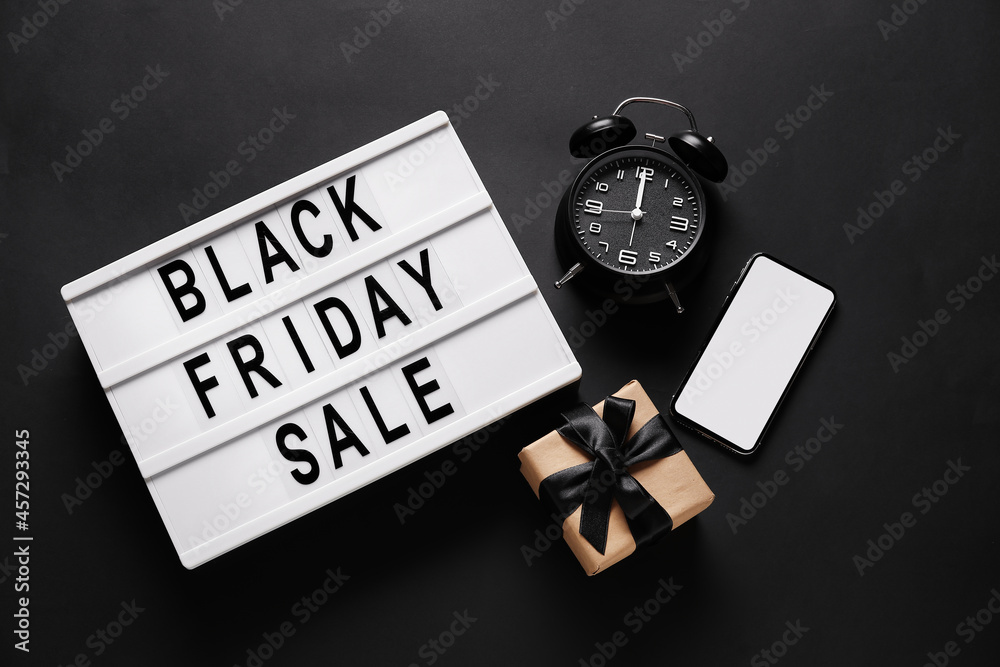 Alarm clock, phone, gift and board with text BLACK FRIDAY SALE on dark background Alarm clock, phone, gift and board with text BLACK FRIDAY SALE on dark background