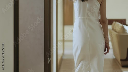 rear view of Asian beauty in white dress walking in living room