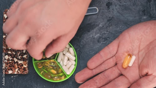 Hand takes sport nutrition yellow capsules of omega 3 supplements, amino acids, creatine, glucosamine and vitamins, top view photo