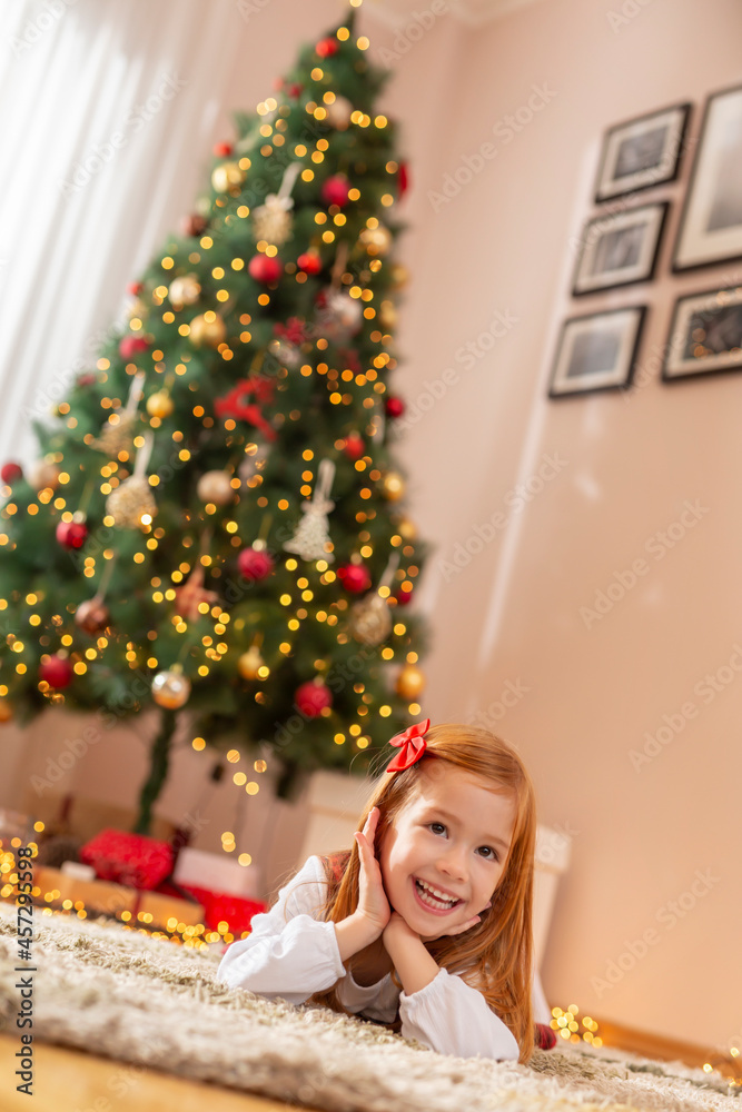 Little girl lying on the floor next to a Christmas tree Little girl lying on the floor next to a Christmas tree