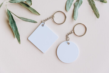 Keychain mockup among olive leaves to display design. Blank white sublimation key chain photo.