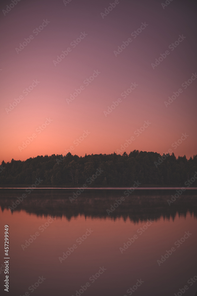 Naklejka premium Calm lake water with pink sunset