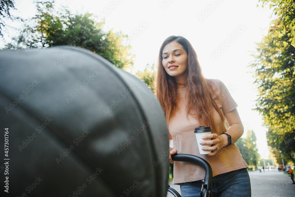 family, child and parenthood concept - happy mother walking with baby stroller in park. family, child and parenthood concept - happy mother walking with baby stroller in park.
