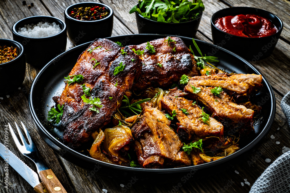 Fototapeta premium Tasty roasted ribs with onion and garlic on wooden table