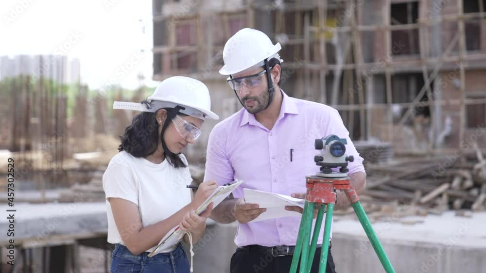 Two Indian man and woman Civil Engineers work at Construction Site outdoor.Two Asian worker checking work details while using theodolite.two civil engineers doing a survey on a construction site. Two Indian man and woman Civil Engineers work at Construction Site outdoor.Two Asian worker checking work details while using theodolite.two civil engineers doing a survey on a construction site.