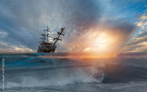 Sailing ship in storm sea on the foreground power sea wave at sunset