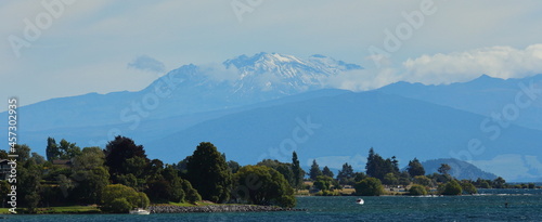 Landscape layers on a cloudy day, with Mount Ruapehu in the distance, and trees in the foreground, looking over Lake Taupo, from Taupo, New Zealand