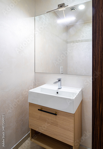 Modern interior of bathroom. White sink with wooden drawer.