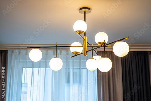 Modern designed chandelier with burning lamps. Contemporary interior.