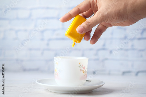Fotografie young women putting artificial sweetener in tea,