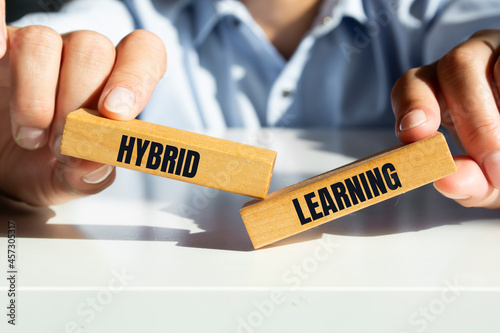 Hybrid learning symbol. Concept words 'Hybrid learning' on wooden blocks. Businessman hand. Business, educational and hybrid learning concept, copy space. photo
