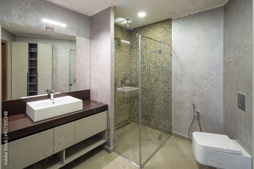 Modern interior of luxury bathroom. Wooden counter. Marble walls.