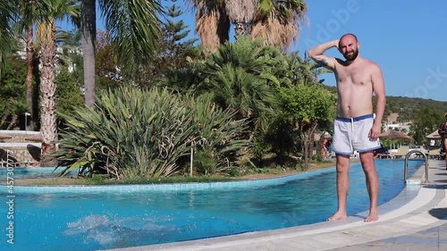 dad and son have fun in swimshorts running and jumping to the swimming pool turning around. photo