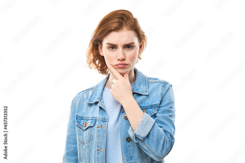 Portrait of red haired dreamy lovely lady, youth. Redhead woman in blue jeans displeased thinks, chooses, decides, dilemmas, isolated white background. Girl student is unhappy Portrait of red haired dreamy lovely lady, youth. Redhead woman in blue jeans displeased thinks, chooses, decides, dilemmas, isolated white background. Girl student is unhappy