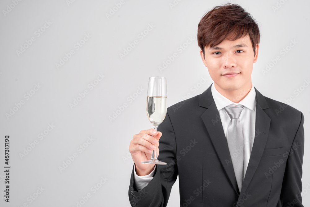 Handsome young businessman in suit and tie cheers with glass of champagne over white background Handsome young businessman in suit and tie cheers with glass of champagne over white background