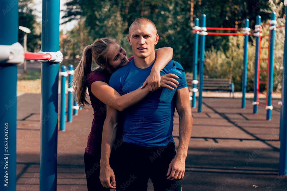 Obraz premium loving couple fit man and woman embrace at sports ground