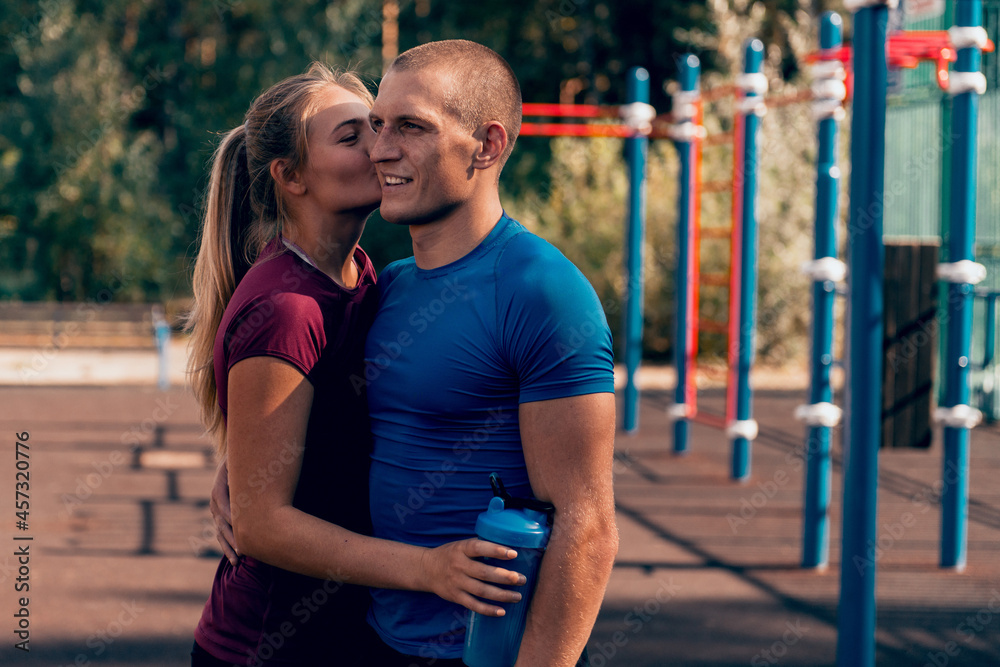 Obraz premium loving couple fit man and woman embrace at sports ground