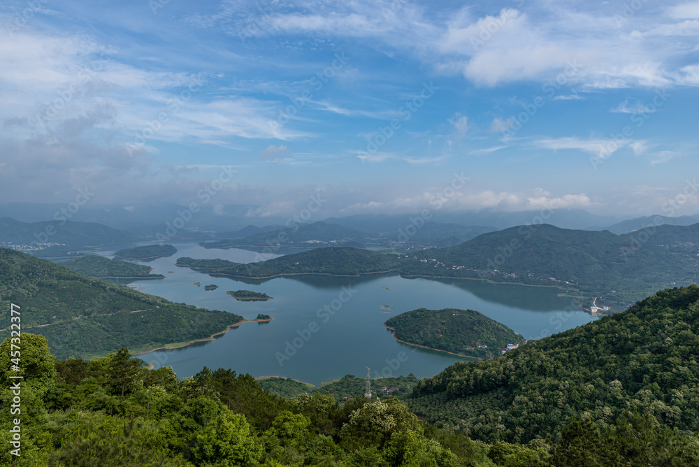 A lake surrounded by forests under blue sky and white clouds A lake surrounded by forests under blue sky and white clouds