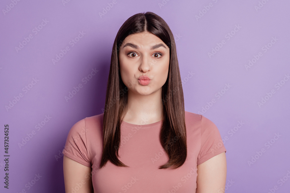 Portrait of pretty girl blowing air kiss with pout lips at camera isolated on purple color background Portrait of pretty girl blowing air kiss with pout lips at camera isolated on purple color background